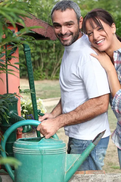 Couple filling up watering can — Stock Photo, Image