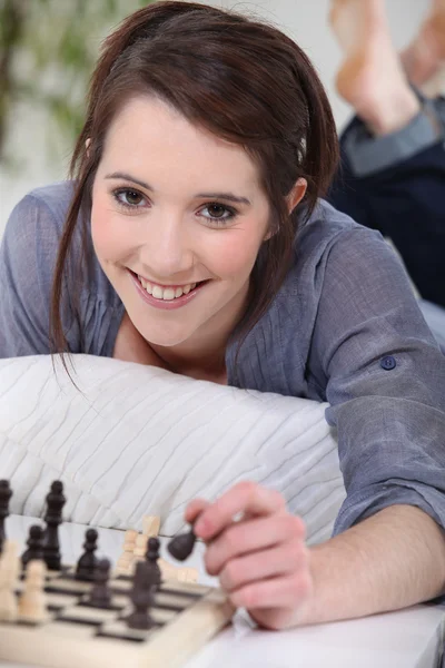 Brunetka na jej kanapie, gra w szachy. — Zdjęcie stockowe