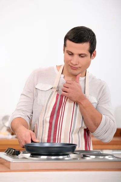Ung man i förkläde matlagning — Stockfoto