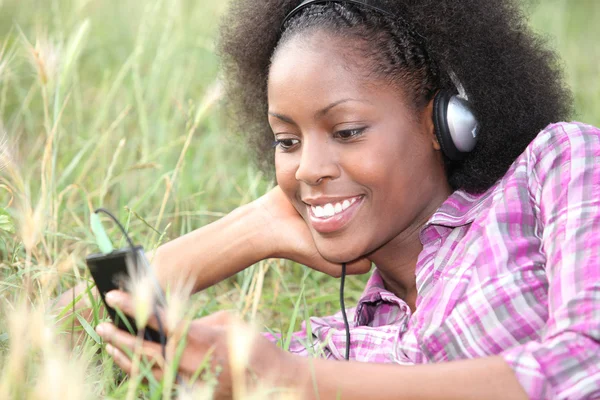Woman listening to music in a field of grass — Stock Photo, Image