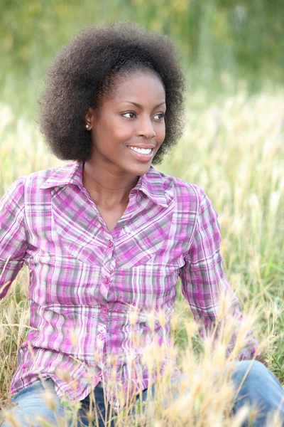Black woman sitting and relaxing in a field — Stock Photo, Image