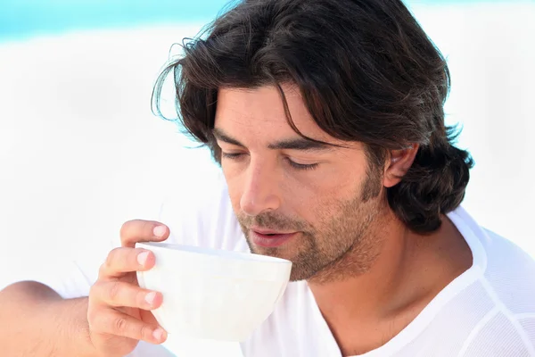 Man drinking coffee by swimming pool — Stock Photo, Image