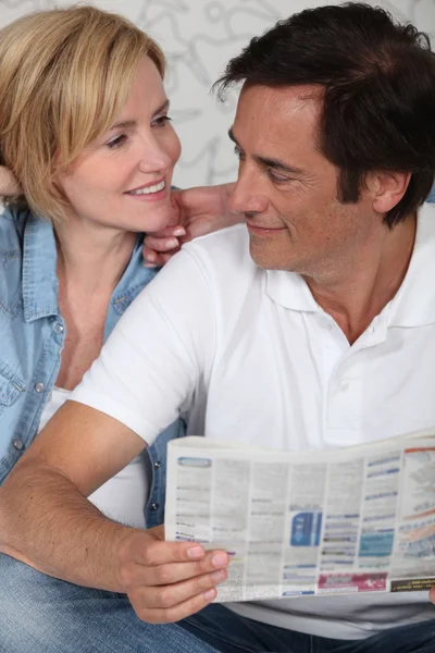Couple looking at newspaper — Stock Photo, Image