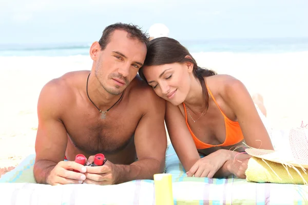 Paar liegt auf Handtuch am Strand — Stockfoto