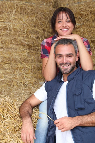 Фермерская пара сидит среди тюков сена — стоковое фото