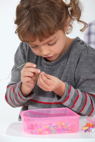 Adorable little girl making necklace — Stock Photo, Image