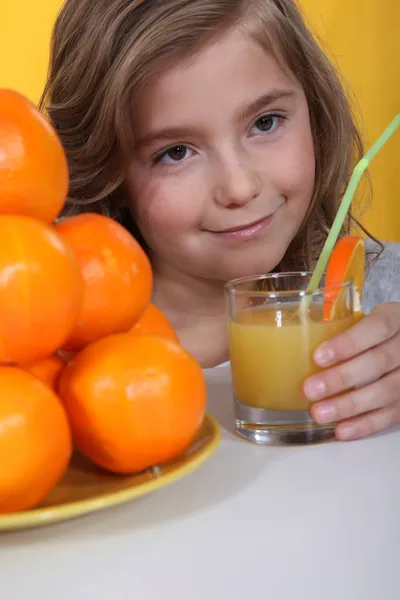 오렌지 주스를 마시는 작은 금발 소녀 — 스톡 사진