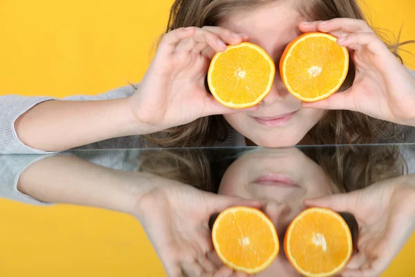 Girl with orange halves in front of her eyes — Stock Photo, Image