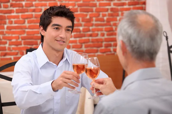 Młody człowiek i starszy chinking kieliszki do wina — Zdjęcie stockowe