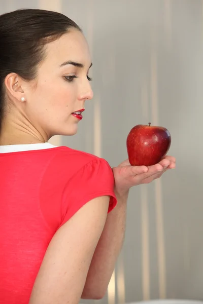 Женщина в красном держит красное яблоко — стоковое фото