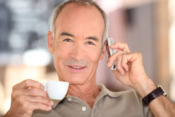 Kahve içme ve Mobil telefonla konuşan gri saçlı adam — Stok fotoğraf