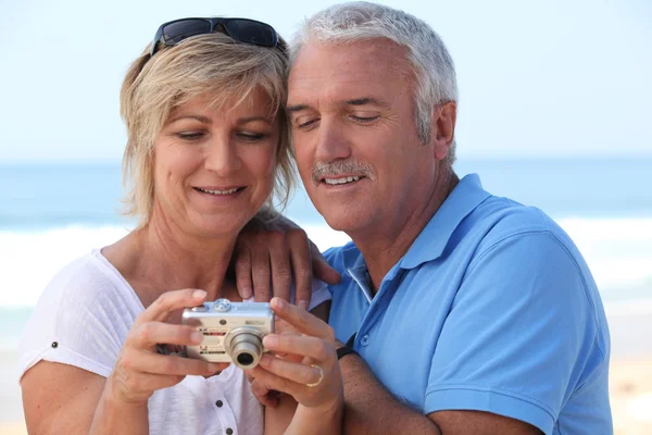 Ouder paar kijken naar de foto's op hun digitale camera — Stockfoto