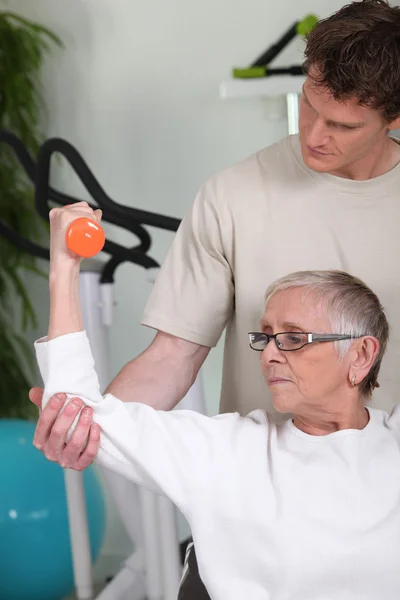 Donna anziana che solleva manubri con allenatore di fitness — Foto Stock