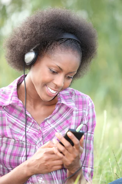 Vrouw luisteren naar muziek via koptelefoons in veld — Stockfoto