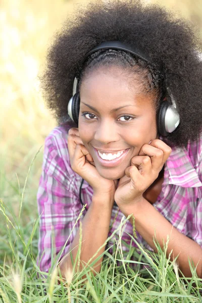 Mulher negra ouvindo música através de fones de ouvido — Fotografia de Stock