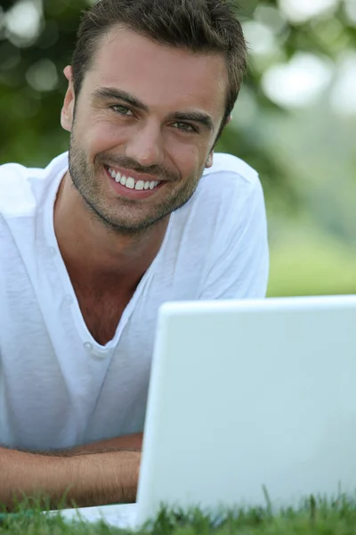 Усміхнений чоловік на відкритому повітрі з ноутбуком — стокове фото