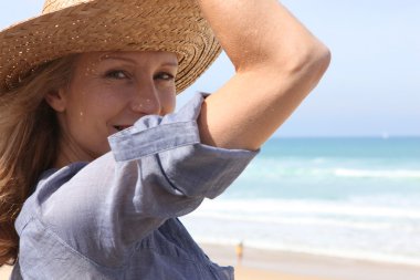 Woman holding onto her straw hat in a breeze clipart