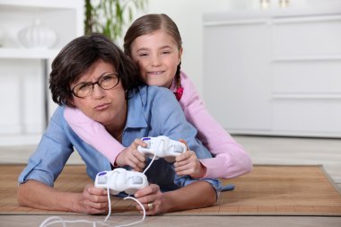 Young girl playing a video game with her grandmother clipart