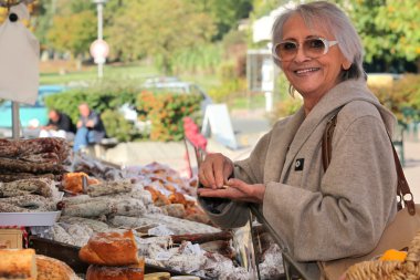 A senior woman in an open-air market clipart