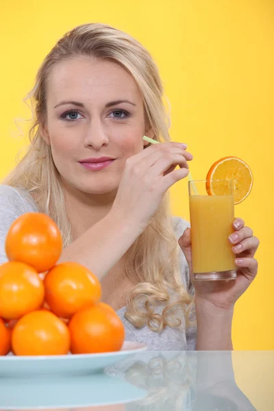 Μια γυναίκα πίνει ένα ποτήρι χυμό πορτοκάλι. — Φωτογραφία Αρχείου