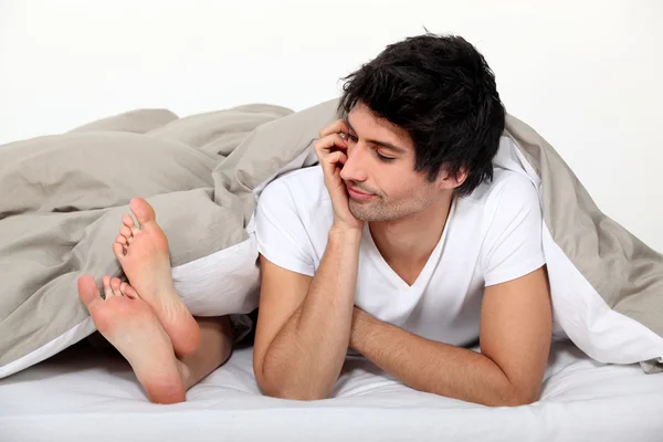 Mann blickt im Bett auf die Füße seiner Partnerin — Stockfoto