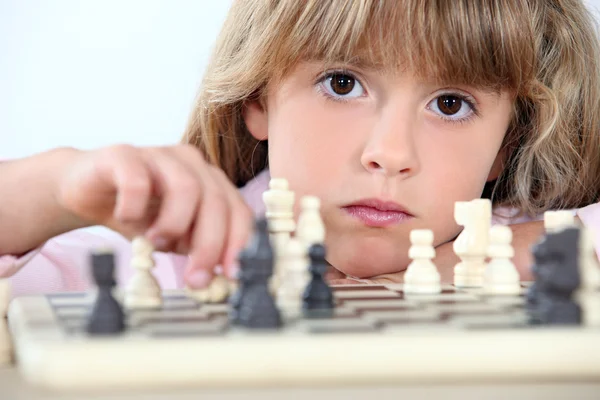 Серьёзная девочка играет в шахматы — стоковое фото