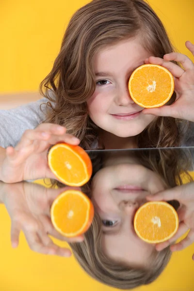 Ένα μικρό κορίτσι με ένα πορτοκάλι κομμένα στη μέση. — Φωτογραφία Αρχείου