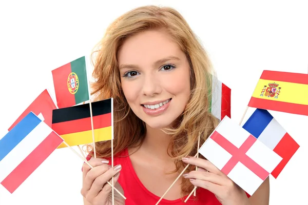 Chica sosteniendo un montón de banderas nacionales —  Fotos de Stock