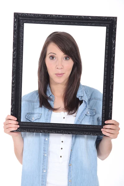 Retrato de una mujer joven sosteniendo un marco — Foto de Stock