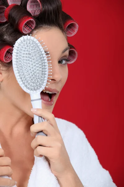 Mulher com encrespadores de cabelo segurando uma escova — Fotografia de Stock