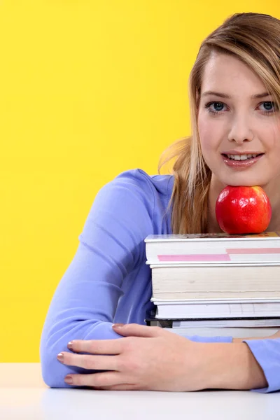 Szőke diáklány jelentő könyvek és almával — Stock Fotó