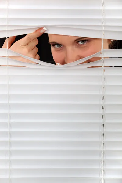 Kobieta, wpatrując się przez kilka blindów — Zdjęcie stockowe