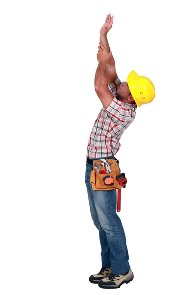 Lavoratore che cerca di toccare il soffitto, colpo in studio — Foto Stock