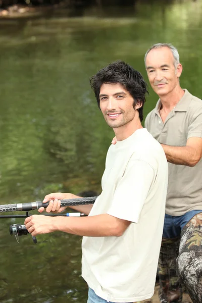Padre e hijo pescando junto a un río — Foto de Stock