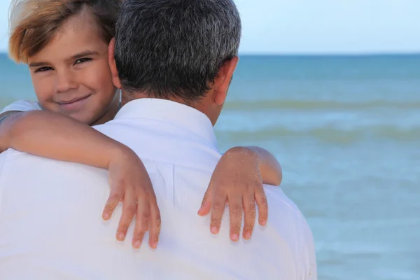 Pappa kramar sin son på stranden. — Stockfoto