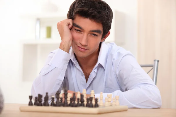 Молодой человек играет в шахматы — стоковое фото