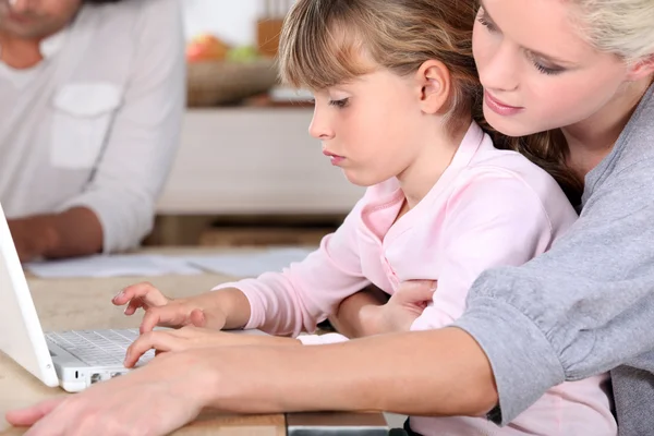 Giovane madre che insegna a sua figlia come usare il computer — Foto Stock
