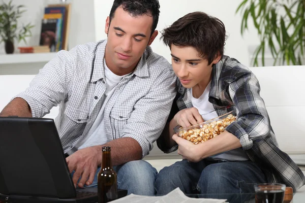 Een vader en zoon over te kijken naar een wedstrijd op een computer. — Stockfoto
