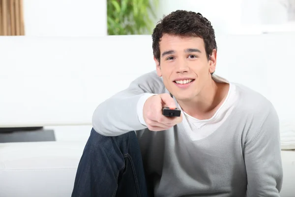 Fiatal ember távirányítóval tv — Stock Fotó