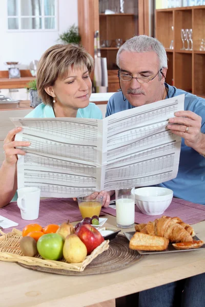 Casal lendo o jornal durante o café da manhã — Fotografia de Stock