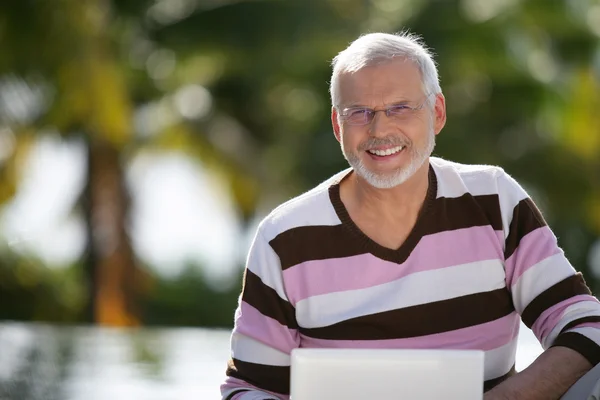Senior man met een laptop in de zon — Stockfoto