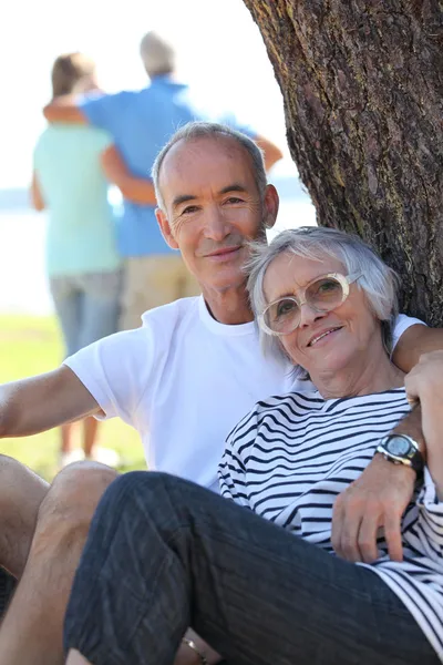 Seniorenpaar sitzt im Sommer an einem Baum — Stockfoto