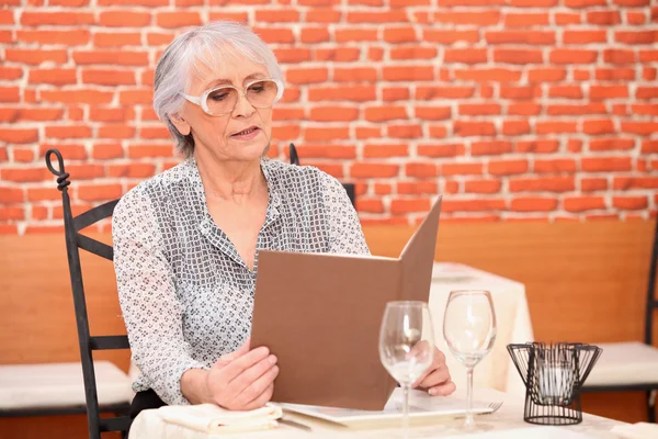 Старша жінка читає меню в ресторані — стокове фото