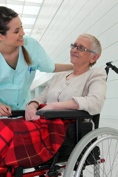 Verpleegkundige praten met een oudere dame in een rolstoel — Stockfoto