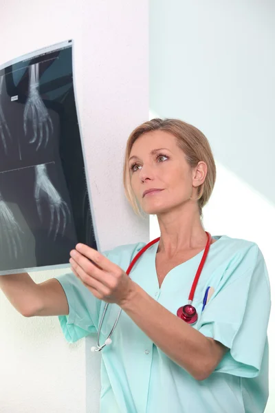 Kvinnlig sjuksköterska undersöker röntgen print — Stockfoto