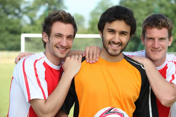 Tre unga fotbollsspelare på en fotbollsplan. — Stockfoto