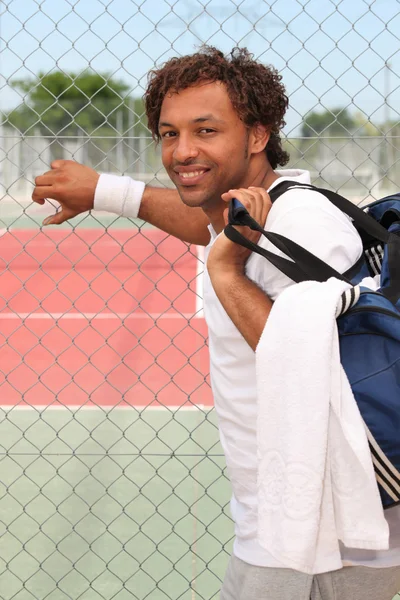Muž stál na tenisový kurt plotem s zpět přes rameno — Stock fotografie
