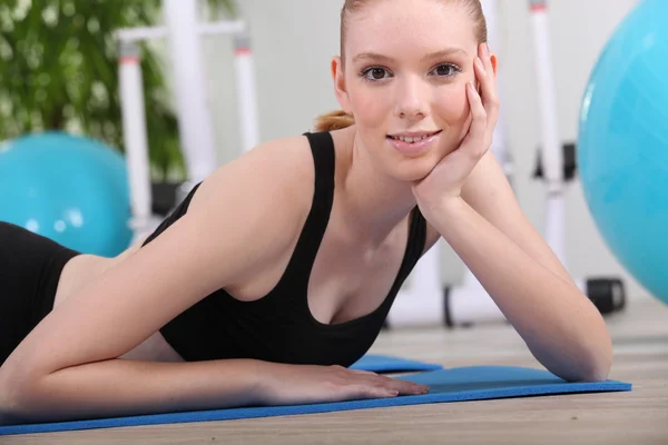 젊은 여자는 체육관 매트에 누워 — 스톡 사진
