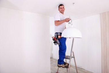 Handy-man fixing ceiling light clipart