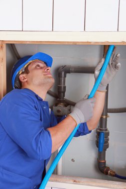 Electrician feeding cable up behind a tiled wall clipart